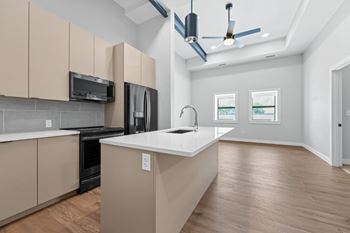 A modern kitchen with wooden floors and beige cabinets at The Avenue Lofts Golden Apartments, Golden, CO